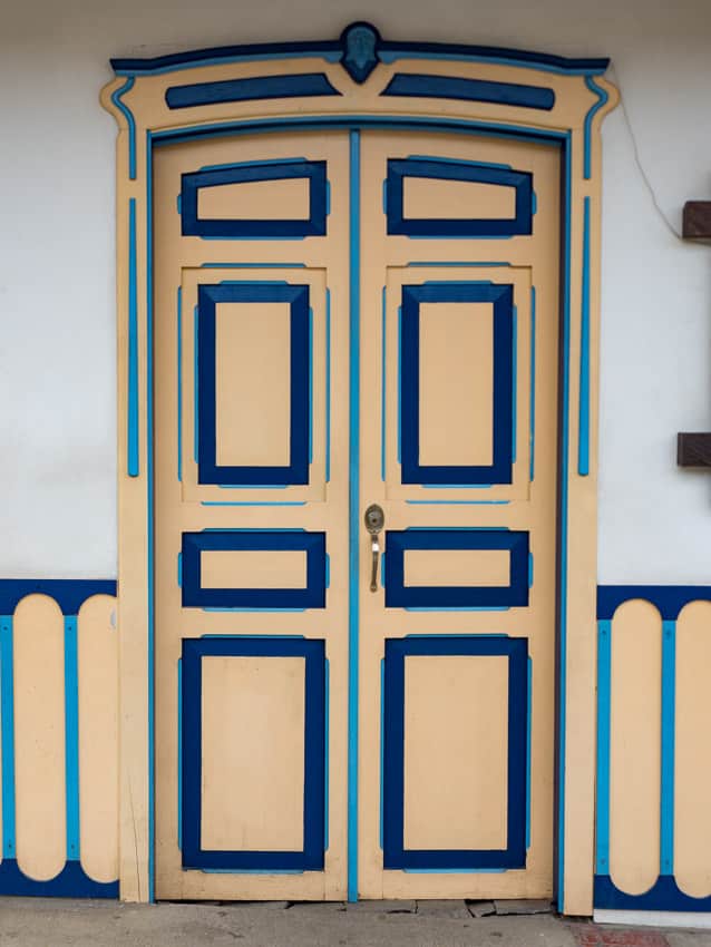 Une porte bleue et jaune sur un bâtiment blanc.