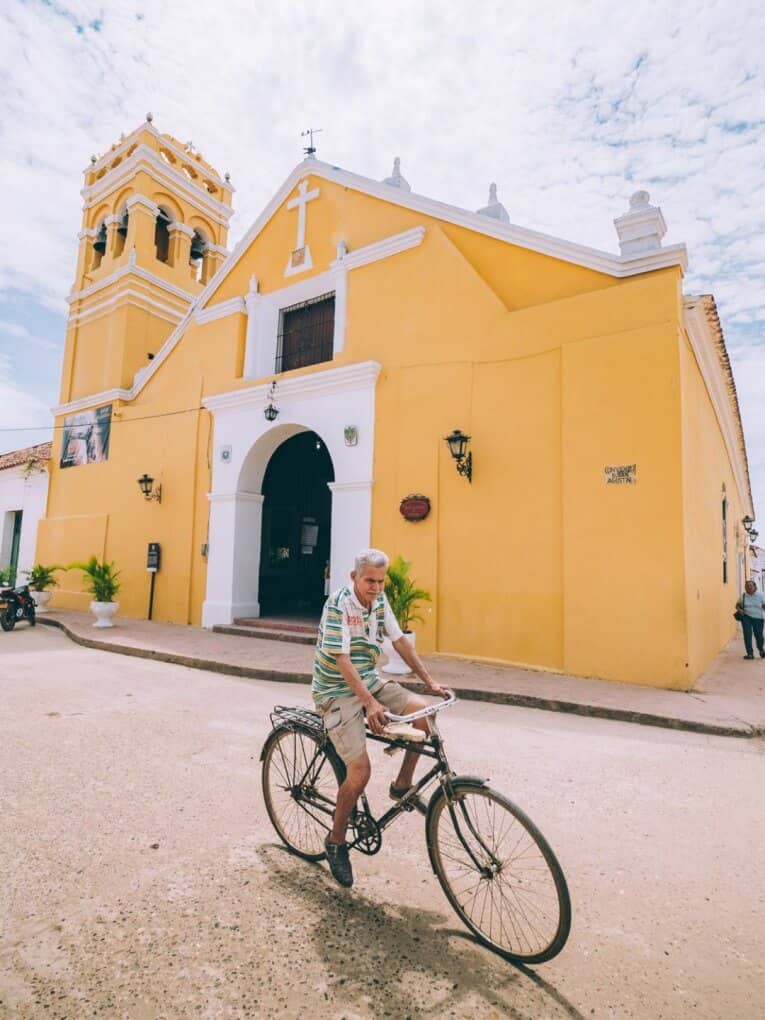Un homme faisant du vélo devant une église jaune à Mompox.