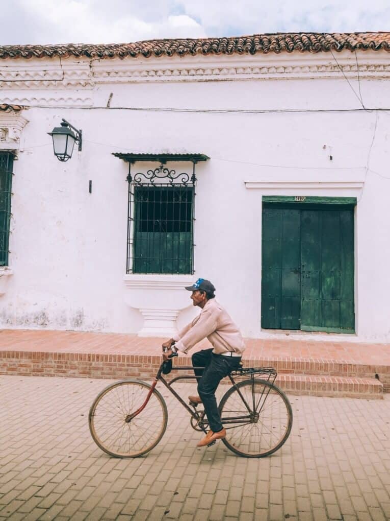 Un homme faisant du vélo devant un bâtiment blanc à Mompox.